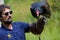 Bearded falconer holds turkey vulture while giving a presentation