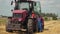 Bearded farmer in overalls near an energy-saturated tractor