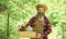 bearded farmer in straw hat with wooden box. mature man gardener working in greenhouse. brutal male carry garden tools