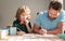 bearded father writing school homework with his boy son in classroom, school