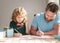 bearded father writing school homework with his kid son in classroom, education