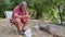 Bearded fisherman sits near a campfire in a tourist camp and preparing the bait for fishing