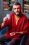 Bearded fortune-teller sitting in armchair and showing divination card