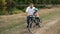 A bearded grandfather teaches his grandson to ride a Bicycle on the river Bank. Family vacation in nature