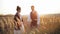 Bearded groom slowly approaches his bride in a beautiful white wedding dress and takes her hand in spikelet field