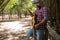 Bearded guitarist with jeans and plaid shirt looking at the smartphone in the forest