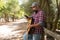 Bearded guitarist with jeans and plaid shirt looking at the smartphone in the forest