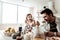 Bearded handsome positive man in a white shirt eating having breakfast with his wife