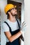 Bearded handyman in goggles and helmet looking at wall