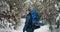 Bearded hiker with backpack walking through winter forest