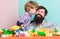 Bearded hipster and boy play together. Dad and child build of plastic blocks. Child care concept. Happy family. Child