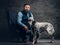 Bearded hunter wearing elegant clothes sitting on a sofa with his white English setter.