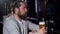 Bearded long haired man looking depressed, drinking beer alone at the bar