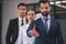 Bearded male showing outstretched hand, his female and male collegues standing behind