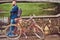 Bearded male with a stylish haircut dressed in casual clothes with a backpack, standing with a retro bicycle near the