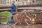 Bearded male with a stylish haircut dressed in casual clothes with a backpack, standing with a retro bicycle near the