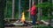 Bearded male tourist warms his hands over a bonfire in the forest