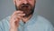 Bearded man with curled up mustache eating chocolate chip cookies on a gray wall background