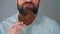 Bearded man with curled up mustache eating chocolate chip cookies on a gray wall background