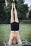 Bearded man doing yoga in the green park. Headstand.