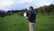 A bearded man dressed in the down jacket watching his tablet and smiling while piloting the drone in the fields