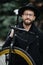 Bearded man with a fixie bicycle. Low angle view of confident young bearded man carrying his bicycle on shoulder and looking at