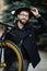 Bearded man with fixie bicycle. Low angle view of confident young bearded man carrying his bicycle on shoulder and looking away