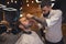 Bearded man getting beard haircut by hairdresser at barbershop.