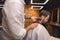 Bearded man getting beard haircut by hairdresser at barbershop.