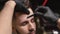 Bearded man getting correction of eyebrows in barbershop