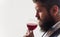Bearded man with glass of red wine. Winemaker or sommelier smelling wine in wineglass. Copy space.