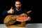 Bearded man with a ham knife ready to cut a piece of typical Spanish ham isolated on black studio background. Super foods.