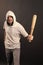 Bearded man hold baseball bat. Hooligan wear hood in hoodie tshirt. Gangster guy threaten with bat weapon. Aggression or