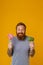 Bearded man holding lollipop and broccoli standing over background