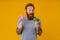 Bearded man holding lollipop and broccoli standing over background