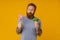 Bearded man holding lollipop and broccoli standing over background