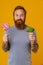 Bearded man holding lollipop and broccoli standing over background