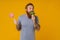 Bearded man holding lollipop and broccoli standing over background
