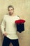 Bearded man holds red rose box on textured wall