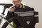 Bearded man inserts bike carrier bag on rear rack of mtb bicycle