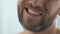 Bearded man looking at teeth in mirror, suffering gum infection pulpitis disease