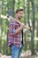 Bearded man in plaid shirt with jeans carry large splitting axe in summer wood natural environment, lumberjack