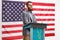 Bearded man on a podium giving a speech and smiling with USA flag behind