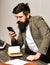 Bearded man in reading glasses with smartphone. Scientist hipster with mobile phone and book. Businessman in suit read