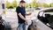 Bearded man refuelling car on gas station and looking into his smartphone. Man compares fuel prices