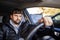 A bearded man sits in the passenger compartment and holds the steering wheel