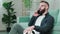 Bearded man standing with soccer ball in hands and talking on the phone.