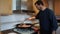 Bearded man stirring chicken and pork meat in a paella