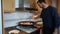 Bearded man stirring chicken and pork meat in a paella