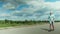 Bearded man in sunglasses on a long board riding near the river Making a stop